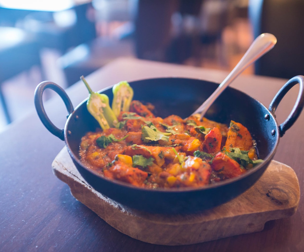Best Curry from Sanam Tandoori, Falkirk Curry in a black bowl resting on a wooden board.