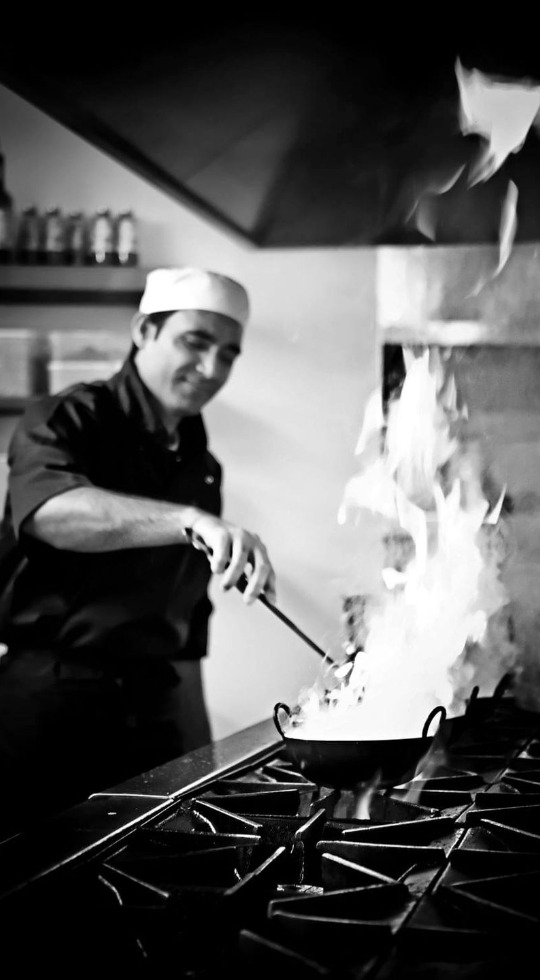 Freshly Cooked Indian Food Chef cooking with flames rising from the pan