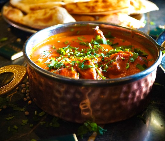 Close up of a bowl of curry with out of focus people in the background
