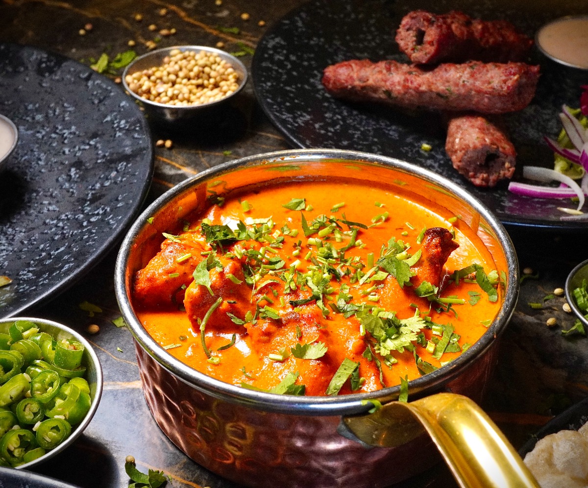 Curry in a black bowl resting on a wooden board.